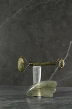 Rodillo Masajeador Facial de Jade con Guasha Verde encima de mesa de marmol