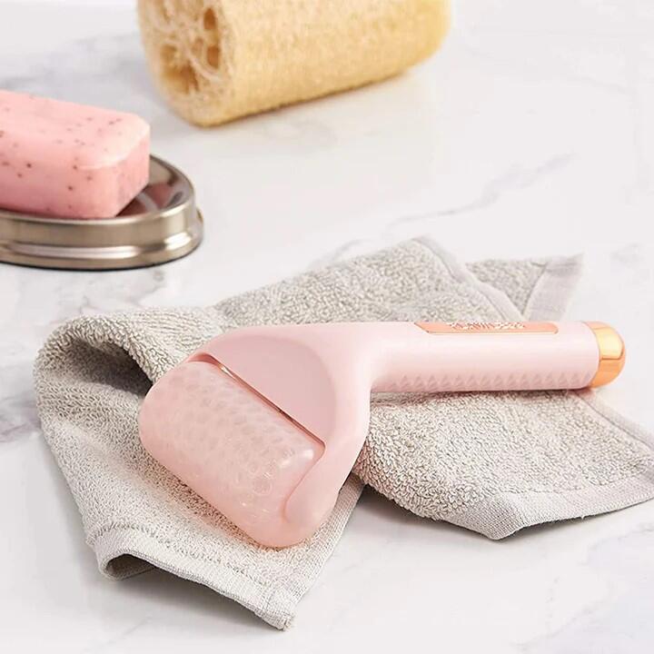 Rodillo Masajeador de Hielo Facial Flawless encima de una toalla
