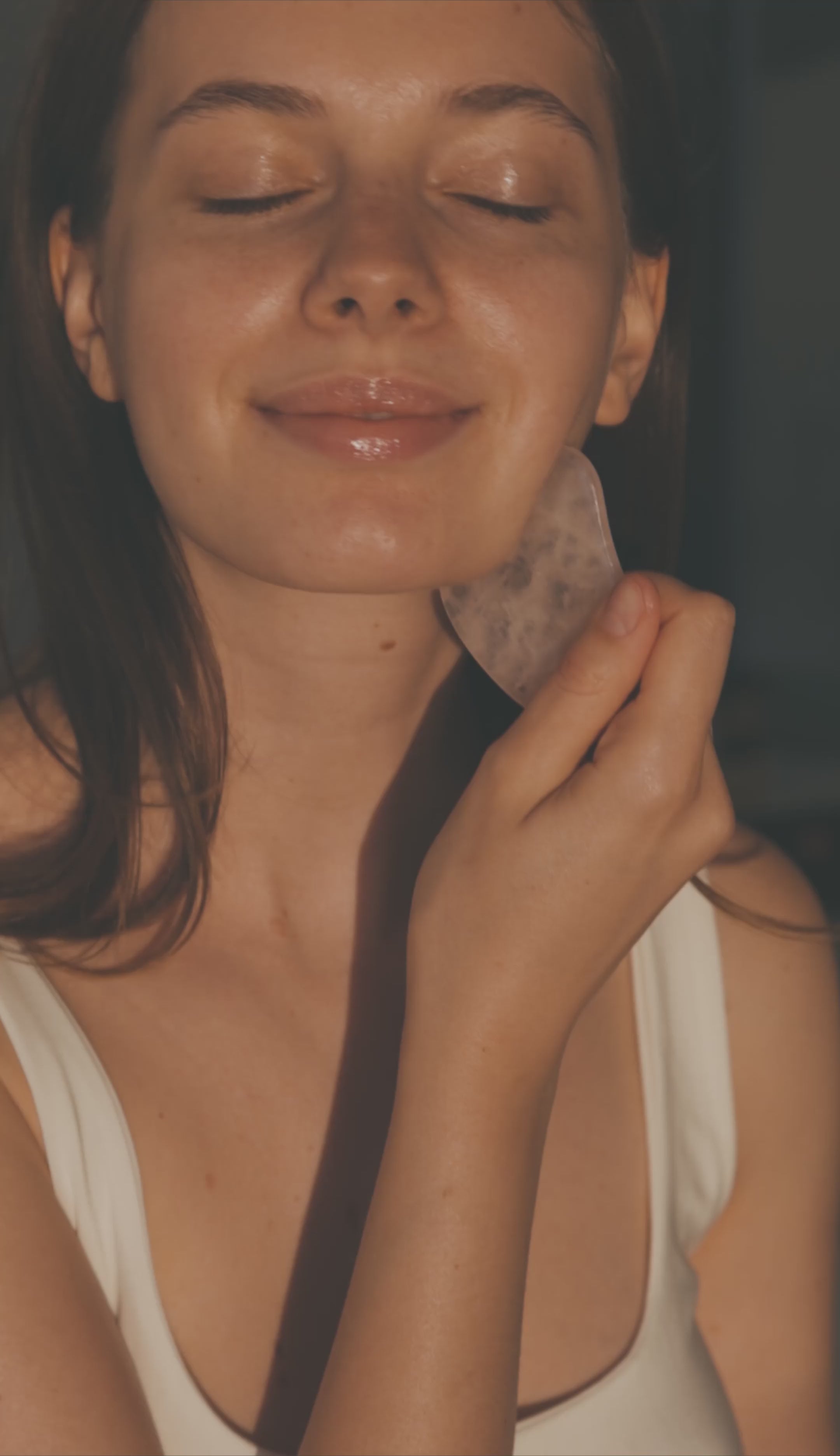 Mujer relajada usando el Rodillo Masajeador Facial de Jade con Guasha 