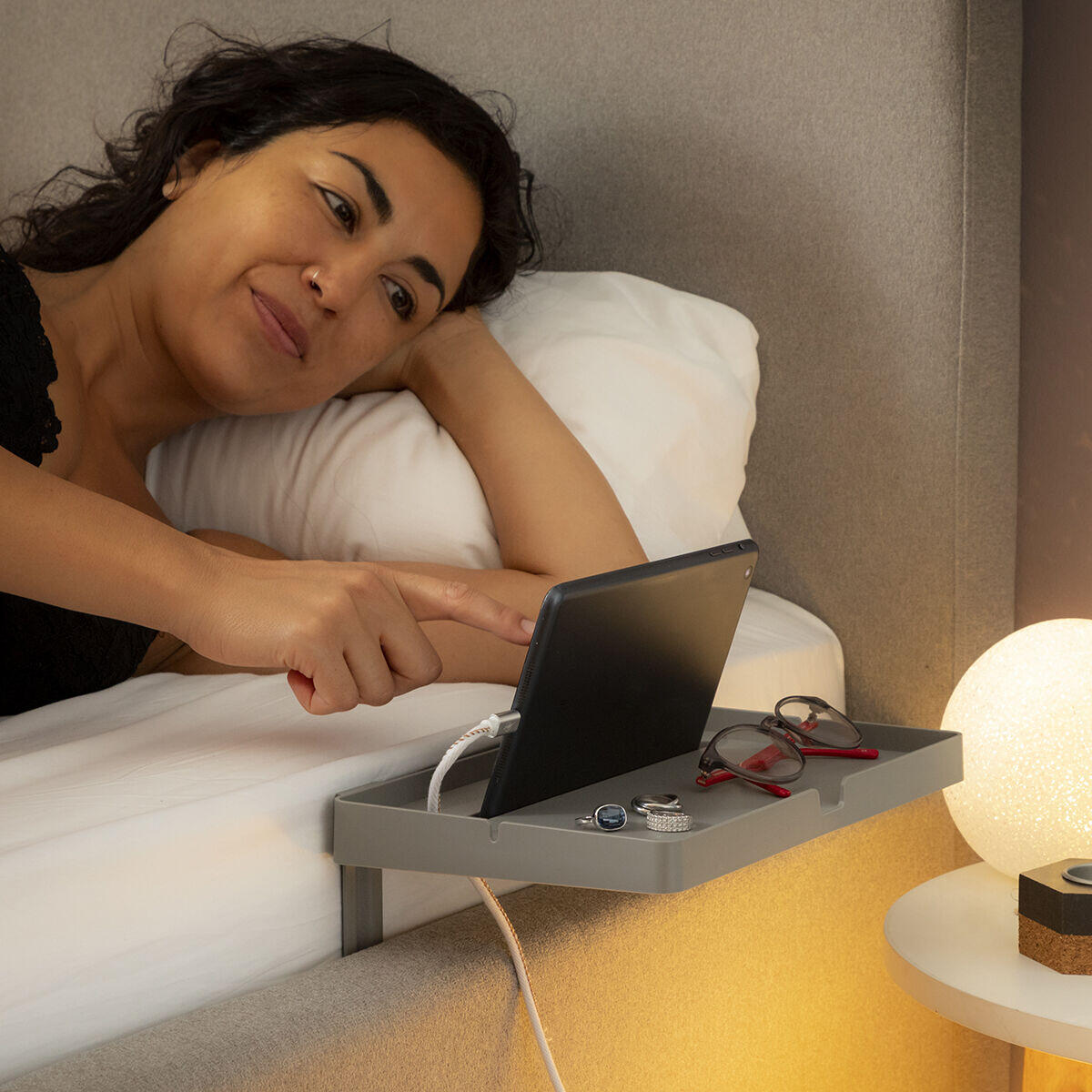 mujer usando su tablet sobre el estante organizador universal para cama
