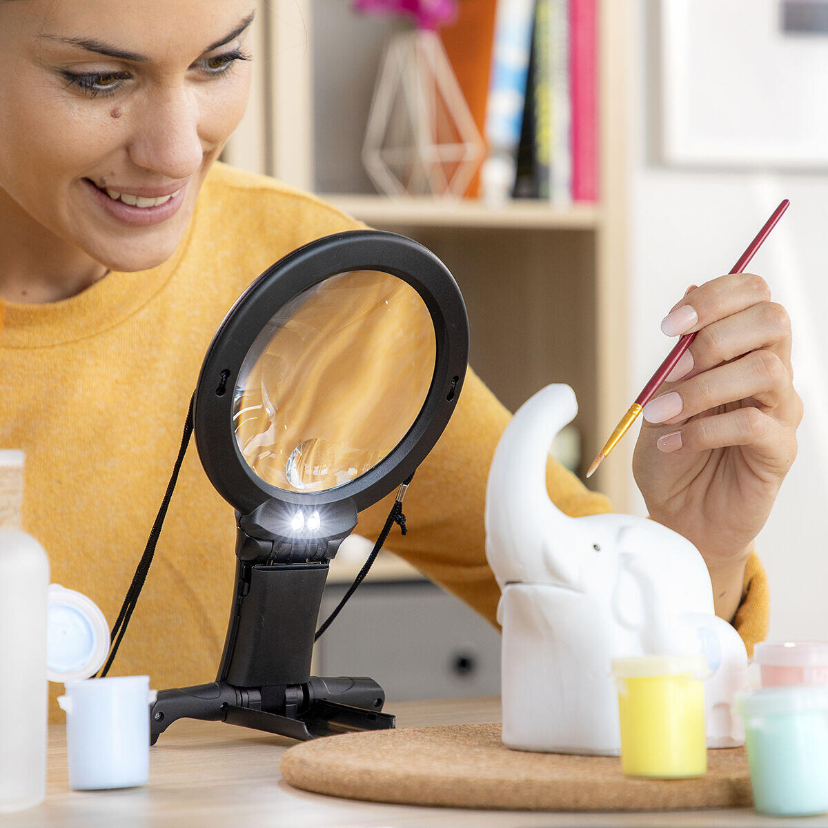 mujer usando Lupa manos libres para ver detalles sobre escultura elefante