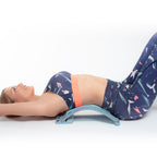 mujer estirandose sobre el soporte corrector de estiramiento lumbar con puntos de presión y magnéticos Lumport 