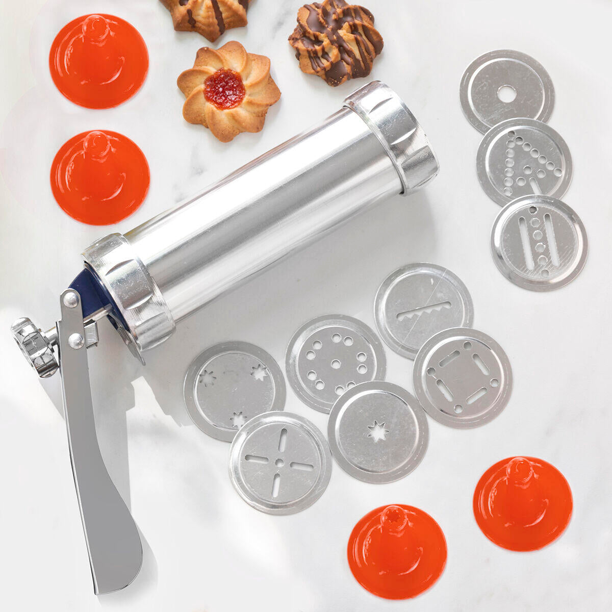 Máquina para Hacer Galletas y Manga Pastelera 2 en 1 Prekies InnovaGoods sobre una mesa con sus accesorios y galletas