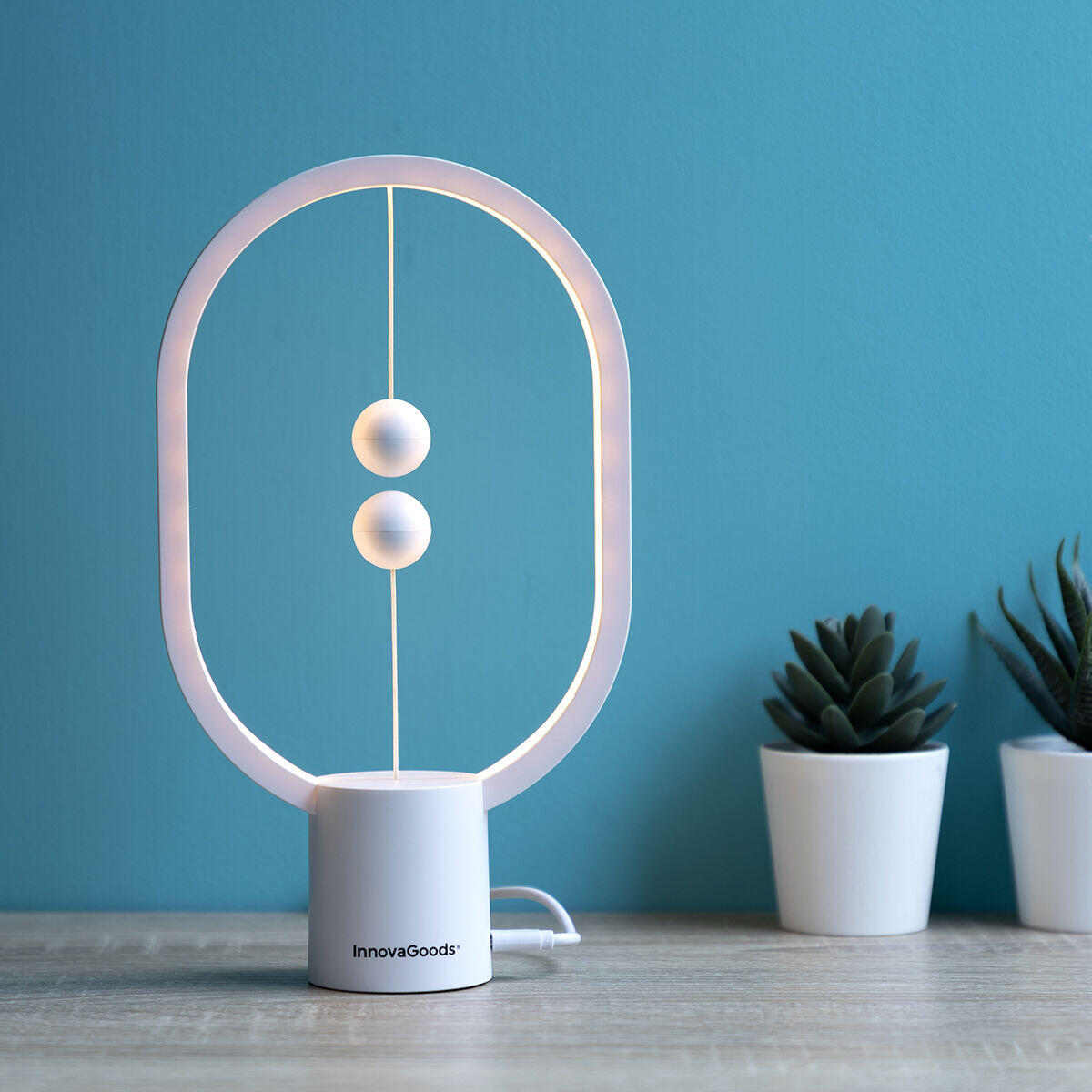 Lámpara de equilibrio con interruptor magnético encendida con fondo celeste sobre mesa