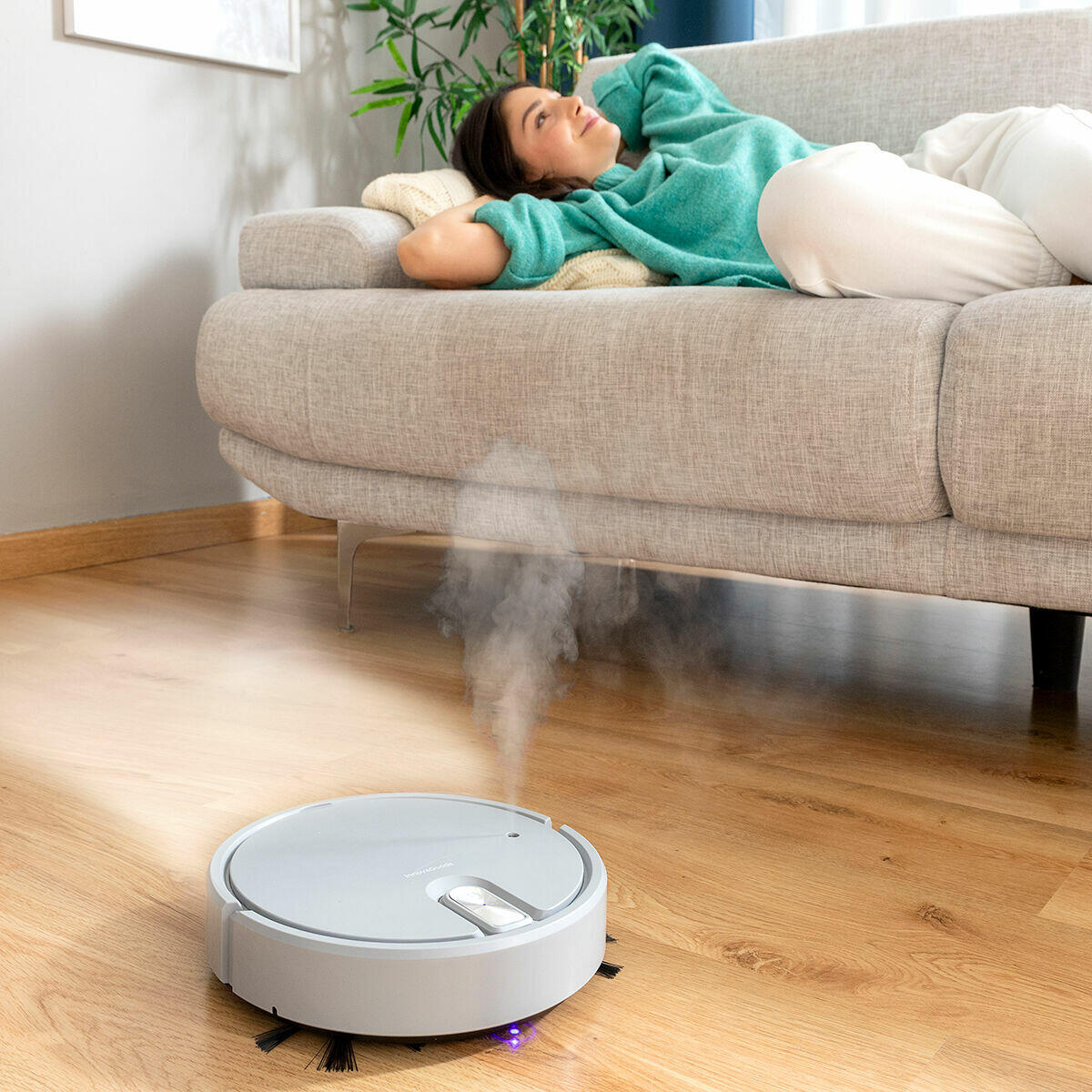 mujer descansando sobre el sofá mientras limpia el Robot Aspirador Recargable Multifunción 5 en 1 Varob