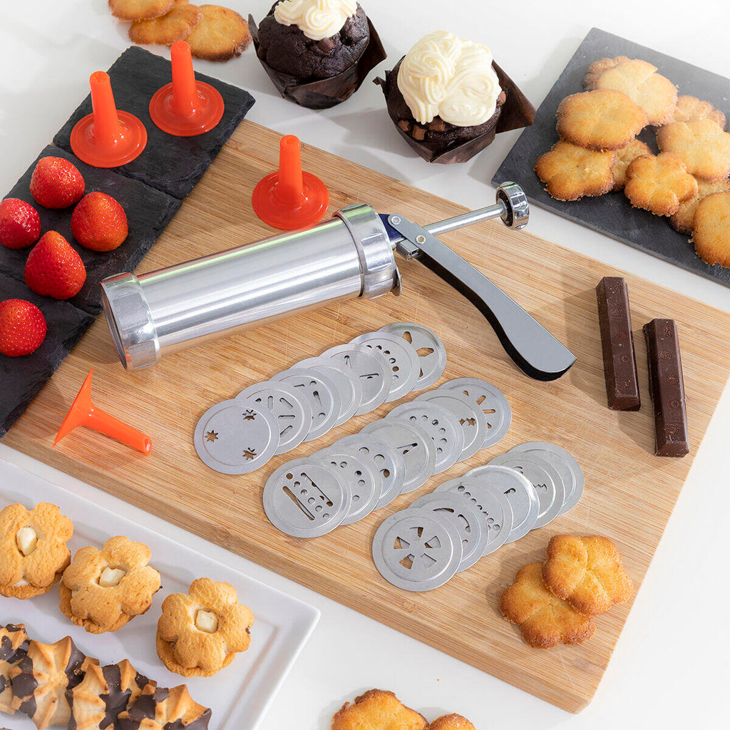 Máquina para Hacer Galletas y Manga Pastelera 2 en 1 Prekies InnovaGoods y accesorios sobre una tabla de cortar
